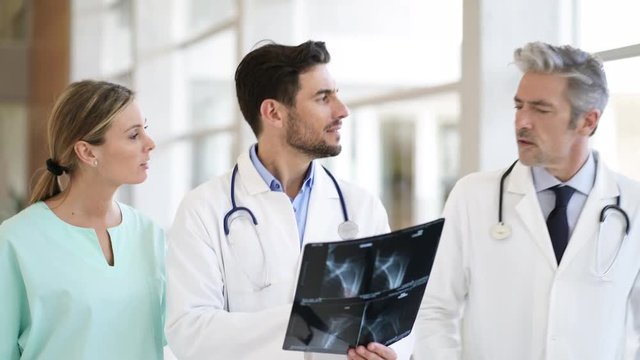 Doctors and nurse talking and walking with X-Ray in modern hospital