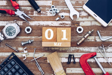 1st May. Happy International Worker's day or Labour Day background concpet.  wooden block calendar 1 May and handy tools and office men's accessories on grunge wooden table texture background.