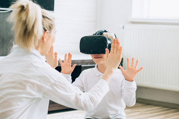 Beautiful blond happy mother playing with her son while using virtual reality headsets at home....