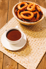 spanish fritters served on a wooden table with a cup of hot chocolate