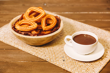 spanish fritters served on a wooden table with a cup of hot chocolate