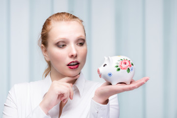 Fototapeta na wymiar young red haired woman with her piggy bank