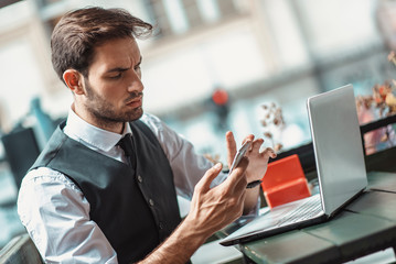 Worried young entrepreneur receiving worrying and bad news over his cell phone