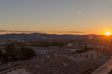 Fototapeta premium A sweeping view of the rooftops of Gubbio at sunset taken from the main Piazza Grande in the town centre with the sun dipping on the far fright of the photo