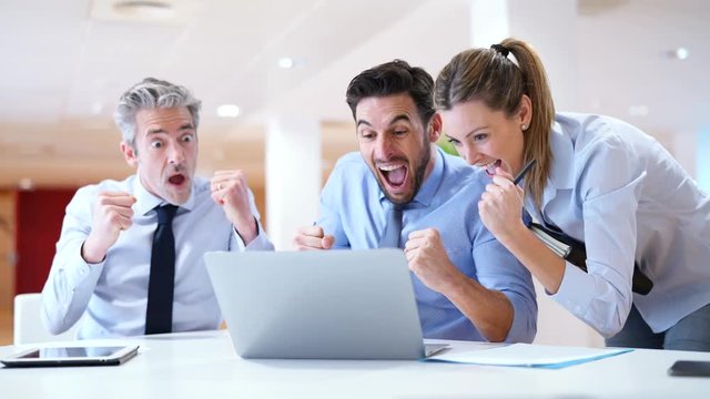 Mixed group of coworkers celebrating results in contemporary office