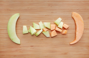 Fresh sliced of green and orange cantaloupe melon on the wooden board background.