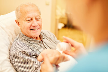 Pflegekraft gibt Senior Mann Tabletten