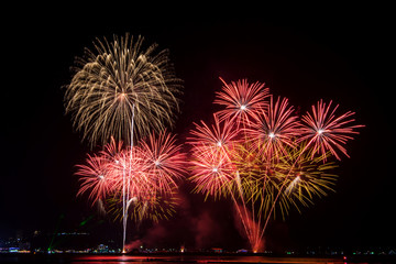 Amazing beautiful colorful fireworks display on celebration night, showing on the sea beach with multi color of reflection on water