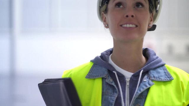 Female construction worker smiling at camera in warehouse