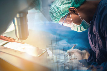 Scientist or doctor working in the operating room with microscope and glassware, medical and science research and development concept 