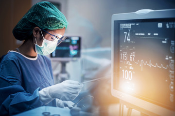 Team of doctors or surgeons with electrocardiogram monitor in hospital surgery operating emergency room showing patient heart rate, medical concept. - obrazy, fototapety, plakaty