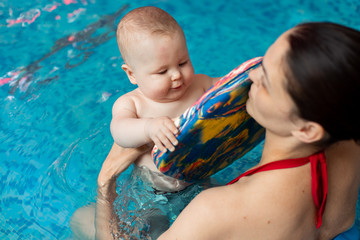 baby with mom learns to swim in the pool