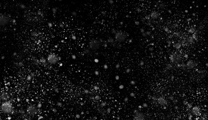 First falling snow bokeh texture on black background. Winter texture.