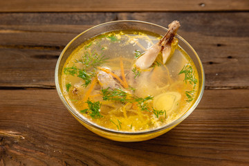 Bouillon quail egg in a transparent round plate on a wooden background