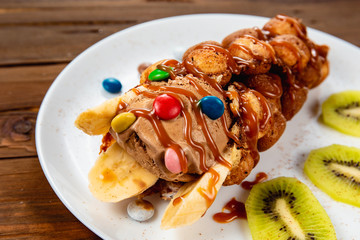 Chocolate ice cream in a waffle cone with candy and fruit syrup