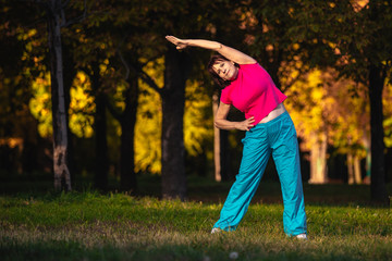 An elderly woman goes in for sports at sunset.