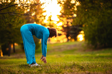 An elderly woman goes in for sports at sunset.