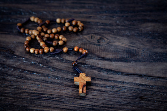 Wooden rosary beads with cross on black wooden background