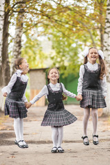 Smiling young children in a school uniform jumping on the road in the park at the day time.