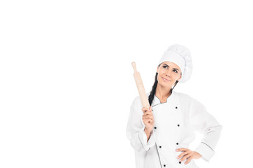 Dreamy chef in hat holding rolling pin isolated on white