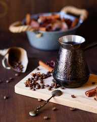 Composition with vintage metal turk for coffee with coffee beans and spices: cinnamon and anise. Served on a white wooden board. Morning routine of good day start. Cozy home inspiration, mood