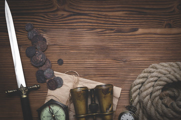Travel or adventure flat lay background with copy space. Adventurer table. Binoculars, pocket watch, coins, old parchment, moorings, compass and pocket watch on the table.