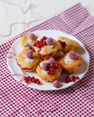 Delicious homemade raspberry cupcakes for a birthday party. Decorated with berries and almond, served on a red festive napkin. White plate. Daylight