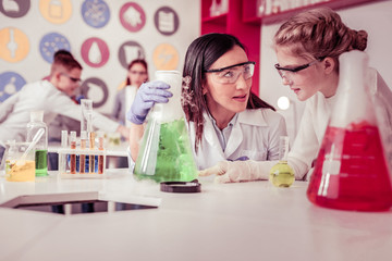 Kind teacher carrying giant tube with green liquid inside