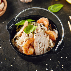Noodles with Shrimps, Chicken, in Metal Bowler with Sesame Seeds on Natural Dark Stone Background