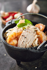 Noodles with Shrimps, Chicken, in Metal Bowler with Sesame Seeds on Natural Dark Stone Background