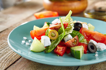 Greek Salad in Blue Plate on Wooden Rustic Background