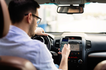 Man driver using smart phone in car modern