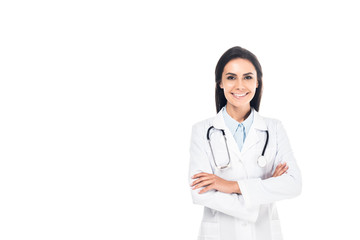 Smiling doctor in white coat standing with folded arms isolated on white