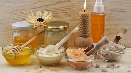 Bee honey in a glass cup, orange gerbera and aromatic salt are placed on the wooden table. Accessories for spa and aromatherapy .