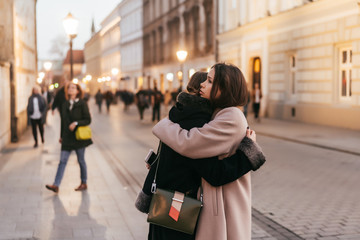 Close-up photo of two emotional woman friends hugging each other