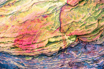 Multicolored rock wall from bottom sediments red orange dark rays crack smooth