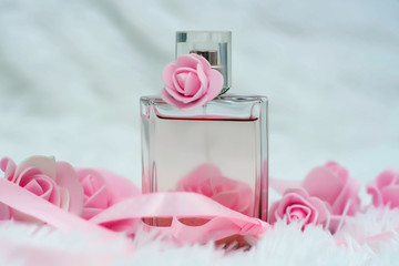 Bottle of perfume with flowers on white fluffy background