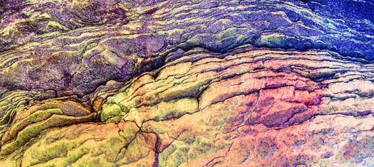 Multicolored rock wall from bottom sediments red orange dark rays crack smooth