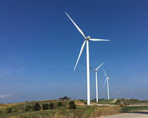 Wind turbines produce energy in the blue sky background