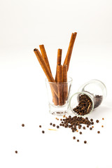 cinnamon and black pepper seeds in a glass, Black pepper is scattered on a white background from glass bottle