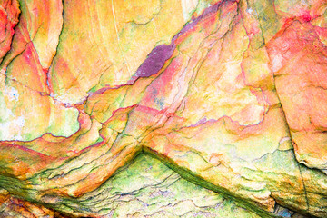 Multicolored rock wall from bottom sediments red orange dark rays crack smooth
