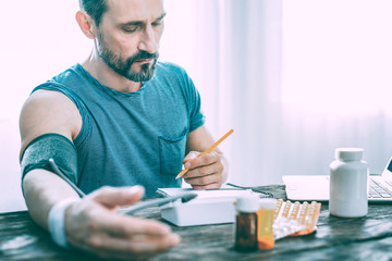 Sad upset man making notes about prescribed pills