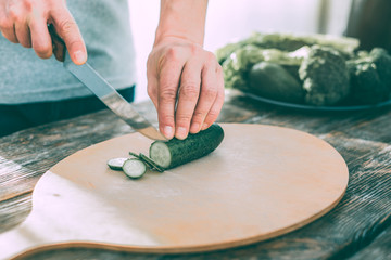 Man cutting cucumbers to make a healthy tasty salad
