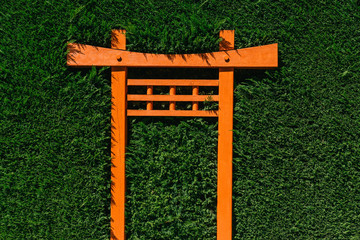 An orange torii gate in a garden hedge.