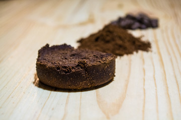 Three stages for preparation of coffee: grain, crushing and the pressed tablet. Wooden surface. Espresso. Work barista.