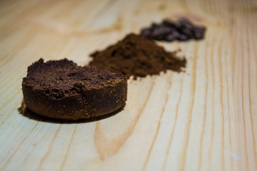 Three stages for preparation of coffee: grain, crushing and the pressed tablet. Wooden surface. Espresso. Work barista.