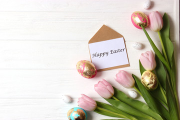 easter composition. Easter eggs and flowers on wooden color background top view. flatlay