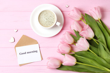 A cup of coffee, a bouquet of flowers and a card with the words 