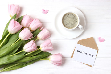 A cup of coffee, a bouquet of flowers and a card with the words "good morning". flatlay