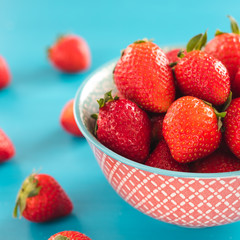 colorful ripe strawberries in a bright bowl on a blue background